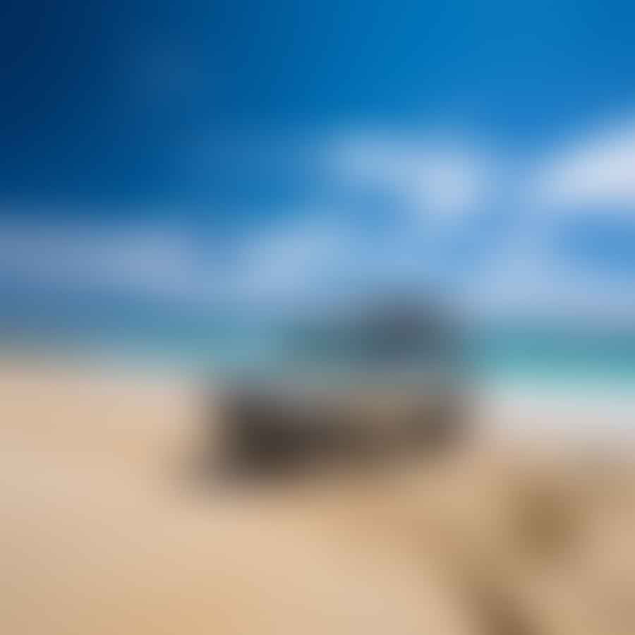 4WD vehicle driving on a beautiful sandy beach with the ocean in the background