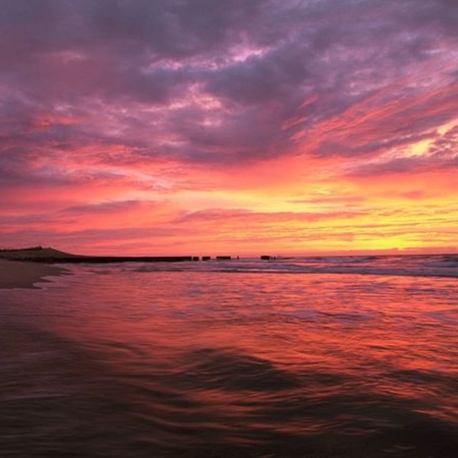 Car driving on Outer Banks beach during sunset