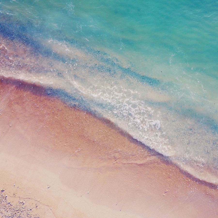 4x4 vehicle driving on a sandy beach during sunset
